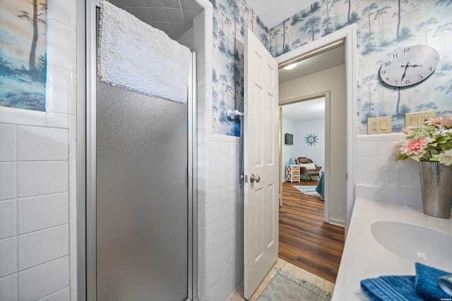206 Shawnee St, Hot Springs, AR 71901 - bathroom featuring wallpapered walls, a shower stall, wood finished floors, tile walls, and a sink