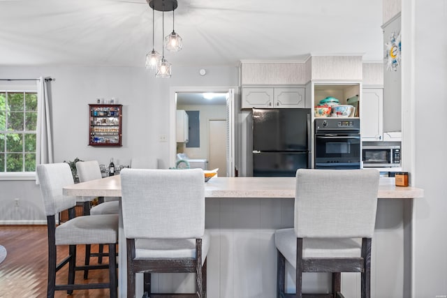 206 Shawnee St, Hot Springs, AR 71901 - kitchen with black appliances, a kitchen bar, light countertops, pendant lighting, and wood finished floors