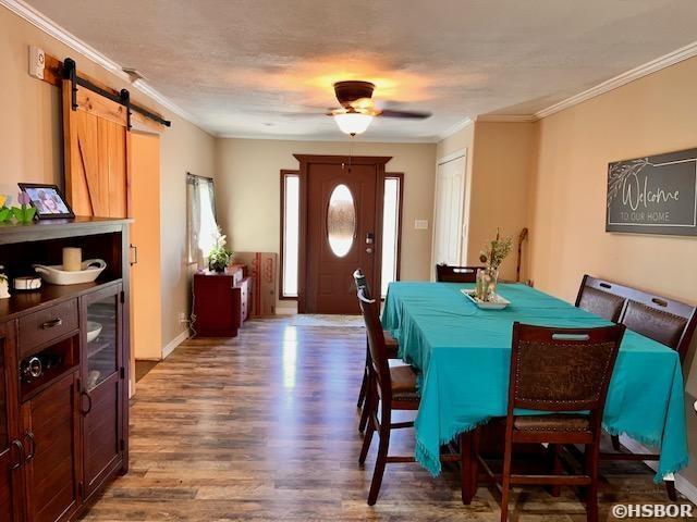906 Surrey Rd, Hot Springs, AR 71909 - dining area featuring a ceiling fan, a barn door, ornamental molding, and wood finished floors