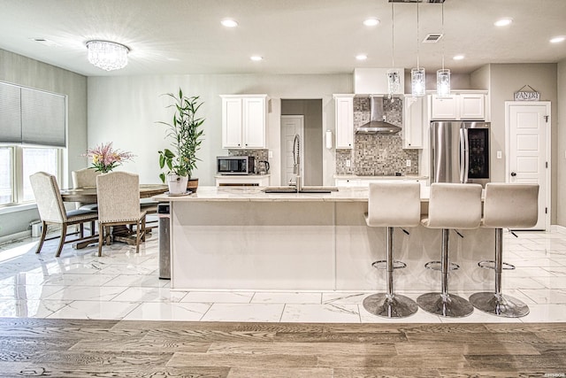 308 Blue Bell Ct, Hot Springs, AR 71901 - kitchen with white cabinetry, hanging light fixtures, appliances with stainless steel finishes, wall chimney range hood, and an island with sink