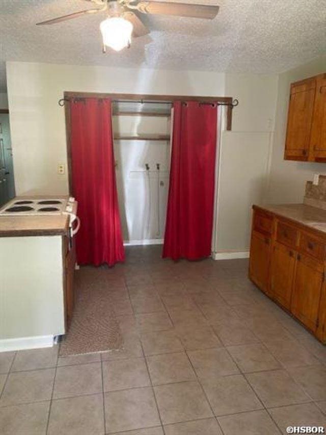 1526 Pearcy Rd, Pearcy, AR 71964 - kitchen with ceiling fan, a textured ceiling, light tile patterned floors, brown cabinets, and light countertops