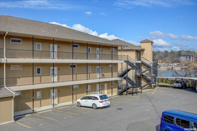 view of building exterior featuring a water view, uncovered parking, and stairway