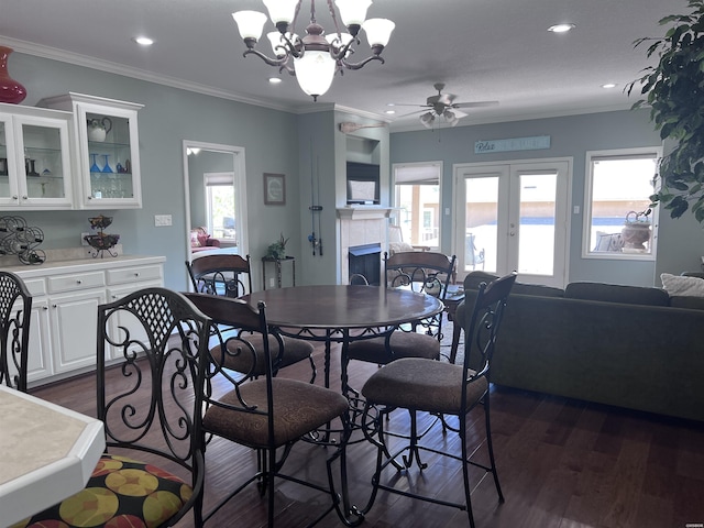 dining space featuring french doors, dark wood-type flooring, a tiled fireplace, and a wealth of natural light