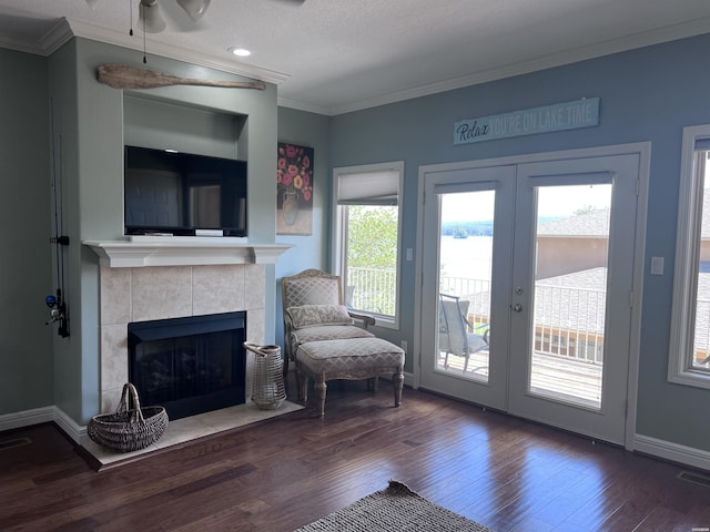 sitting room with dark wood-type flooring, a fireplace, baseboards, french doors, and crown molding