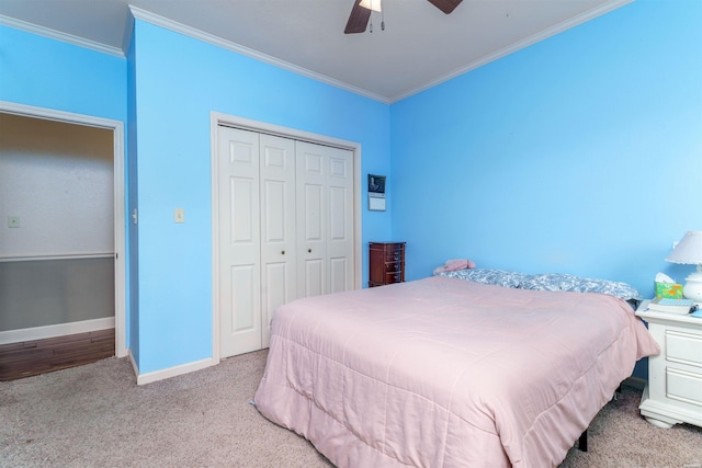 carpeted bedroom featuring crown molding, baseboards, a ceiling fan, and a closet