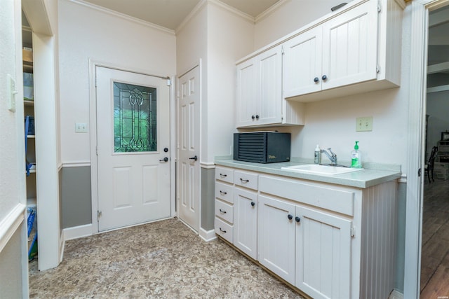 interior space with crown molding, a sink, and baseboards