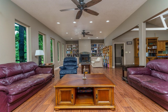living room featuring a ceiling fan, recessed lighting, a glass covered fireplace, and light wood finished floors