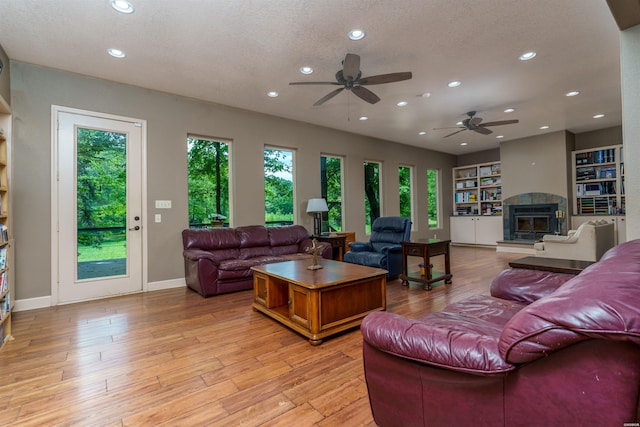 living room with recessed lighting, a ceiling fan, light wood finished floors, and a glass covered fireplace