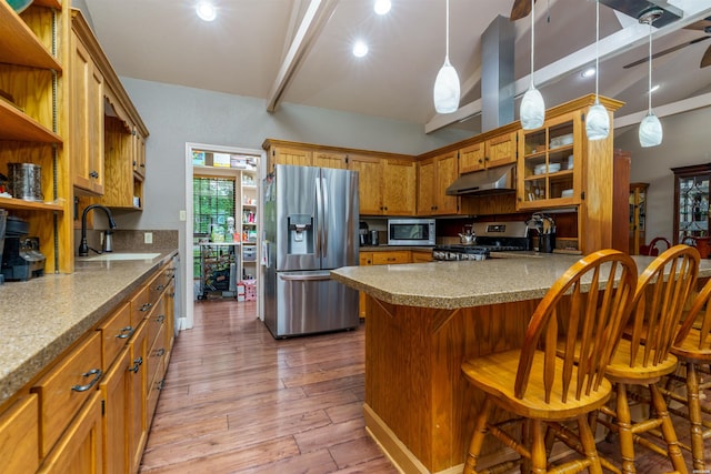 kitchen with open shelves, wood finished floors, under cabinet range hood, a sink, and stainless steel appliances