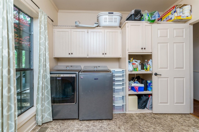 washroom featuring cabinet space, ornamental molding, washer and clothes dryer, and plenty of natural light