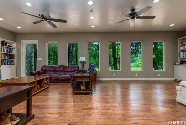 living area with a ceiling fan, a healthy amount of sunlight, and light wood-style flooring
