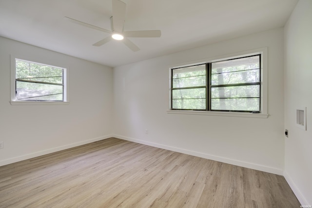 spare room with a ceiling fan, light wood finished floors, and baseboards