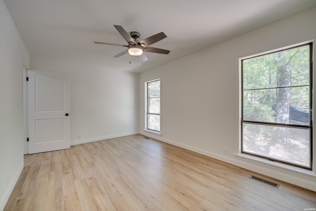 spare room with light wood-style floors, baseboards, visible vents, and a ceiling fan