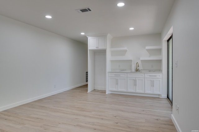 interior space featuring visible vents, baseboards, light wood-type flooring, a sink, and recessed lighting