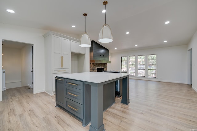 kitchen featuring white cabinets, open floor plan, light countertops, a center island, and decorative light fixtures