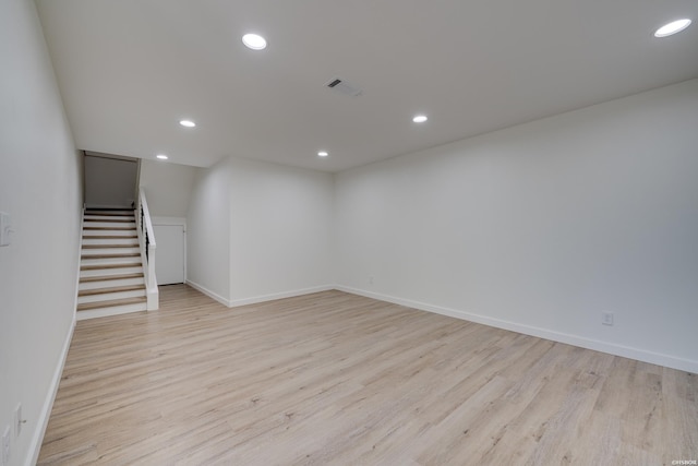 finished below grade area with recessed lighting, visible vents, light wood-style floors, baseboards, and stairs