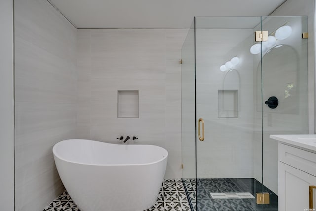 full bath featuring a stall shower, tile walls, a freestanding tub, and vanity