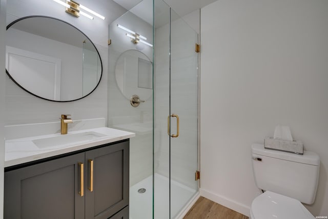 full bathroom with toilet, vanity, a shower stall, wood finished floors, and baseboards