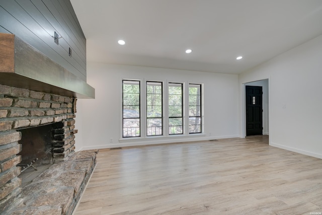 unfurnished living room with baseboards, recessed lighting, a fireplace, and light wood-style floors