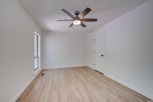 unfurnished room with baseboards, a ceiling fan, visible vents, and light wood-style floors