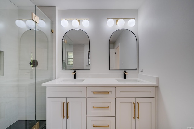 bathroom with a tile shower, double vanity, and a sink