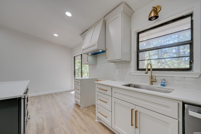 kitchen with dishwasher, backsplash, a sink, and white cabinets