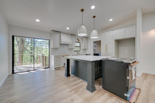 kitchen featuring decorative backsplash, a center island, hanging light fixtures, custom exhaust hood, and light countertops