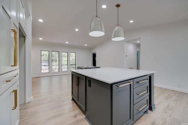 kitchen with light wood-style floors, open floor plan, light countertops, hanging light fixtures, and a center island