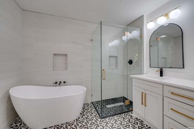 bathroom with a freestanding bath, vanity, a shower stall, and tile walls