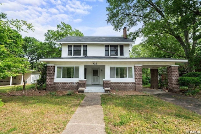 view of front of property featuring a front yard, aphalt driveway, brick siding, and an attached carport