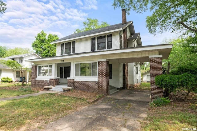 view of front of property with a chimney, brick siding, a carport, and driveway