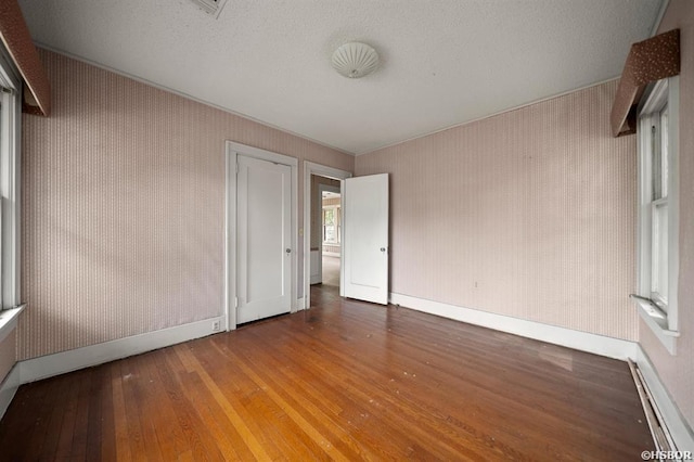 unfurnished bedroom with hardwood / wood-style floors, baseboards, and a textured ceiling