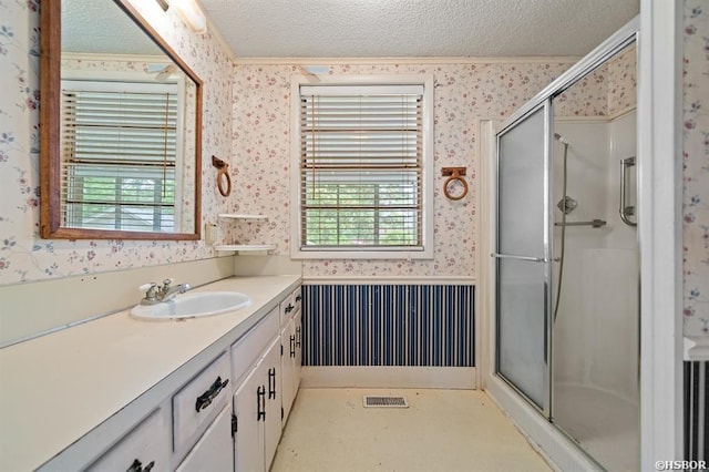 bathroom with a textured ceiling, a shower stall, plenty of natural light, and wallpapered walls