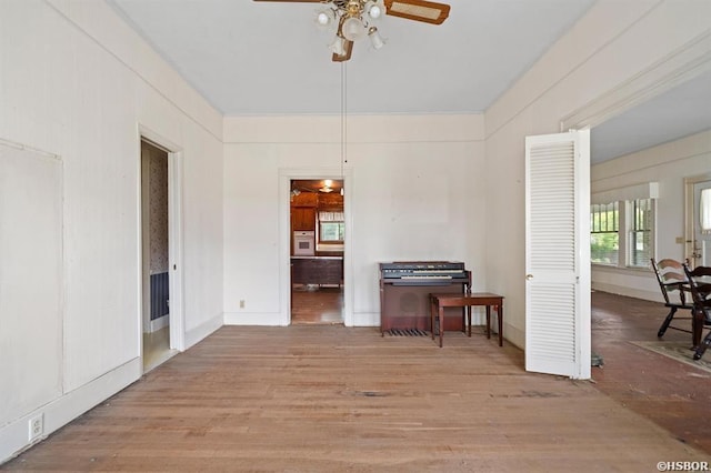 interior space with baseboards, wood finished floors, and a ceiling fan