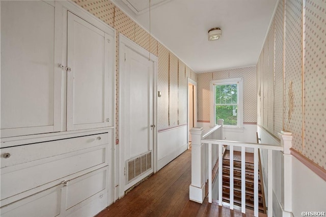 corridor featuring attic access, dark wood-style floors, an upstairs landing, visible vents, and wallpapered walls