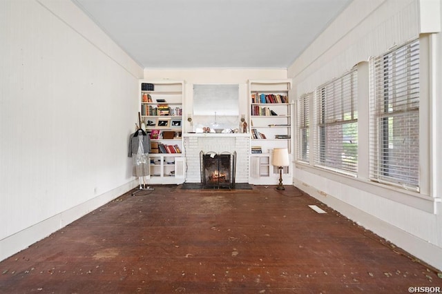 living area featuring hardwood / wood-style flooring, built in shelves, and a brick fireplace
