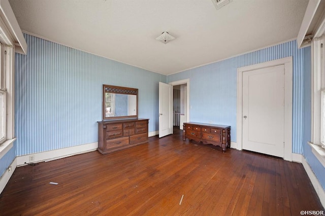 unfurnished bedroom featuring hardwood / wood-style flooring, ornamental molding, and baseboards