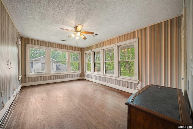 unfurnished sunroom featuring hardwood / wood-style floors, visible vents, and ceiling fan