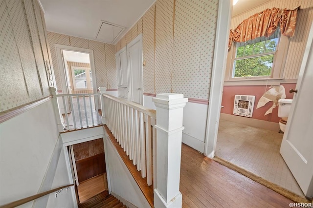 stairway with wallpapered walls, attic access, a wealth of natural light, and heating unit