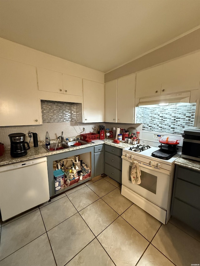 kitchen featuring white appliances, white cabinets, a sink, light countertops, and backsplash