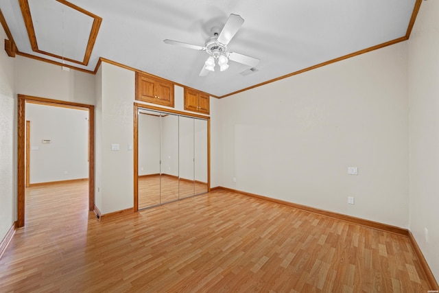 unfurnished bedroom with attic access, visible vents, light wood-style flooring, crown molding, and a closet