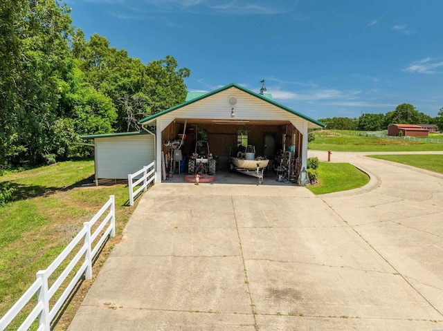 garage featuring concrete driveway and fence