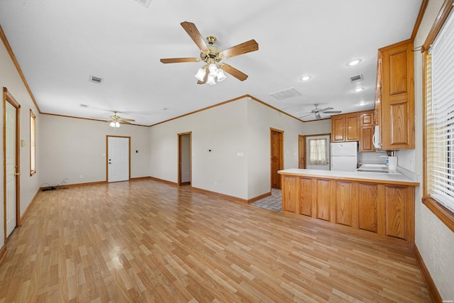 kitchen featuring a peninsula, light wood-style floors, open floor plan, light countertops, and freestanding refrigerator