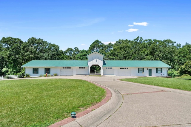 ranch-style house featuring an attached garage, concrete driveway, metal roof, and a front yard