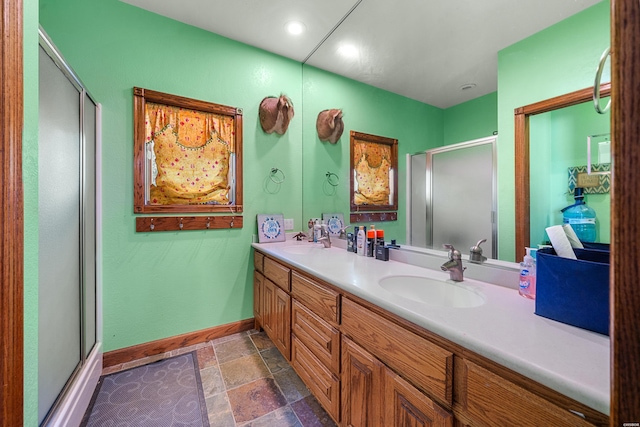 bathroom with double vanity, stone tile flooring, baseboards, and a sink