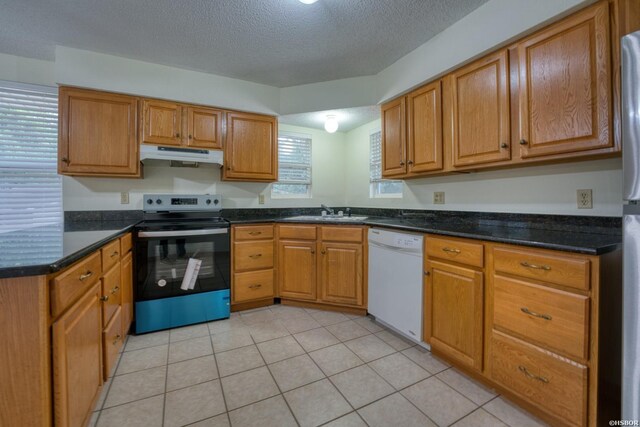 kitchen featuring electric range, brown cabinetry, white dishwasher, a sink, and under cabinet range hood