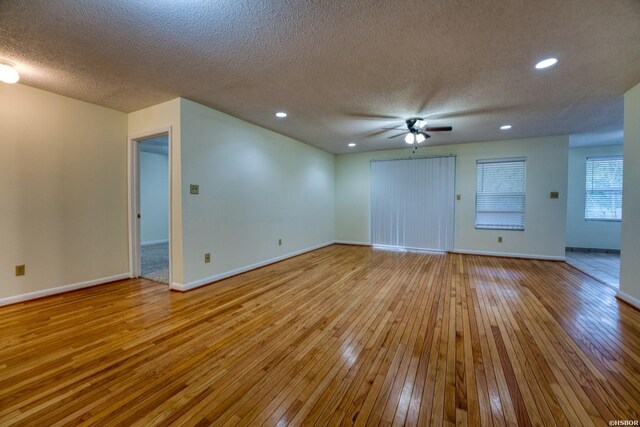 empty room featuring light wood finished floors, a textured ceiling, baseboards, and a ceiling fan