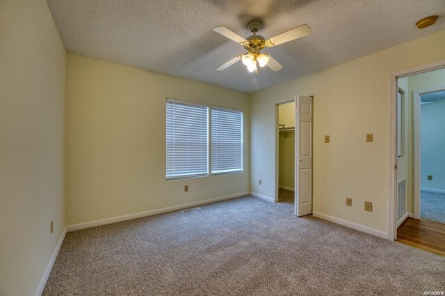 unfurnished bedroom with light carpet, visible vents, baseboards, a ceiling fan, and a textured ceiling