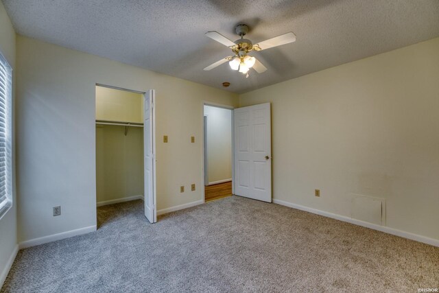 unfurnished bedroom with light colored carpet, a textured ceiling, and baseboards