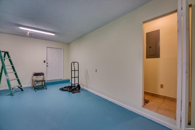 exercise room featuring a textured ceiling, electric panel, and baseboards